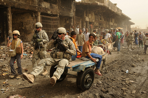 イラク・バグダッドでイラク人の少年の荷車に乗っかるアメリカ兵。2008年5月31日撮影。アメリカ空軍提供。.jpg